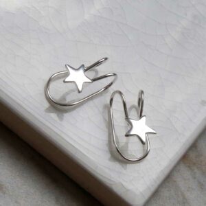 Sterling Silver Star Ear Cuffs sat on a marble tile with their shadow being cast