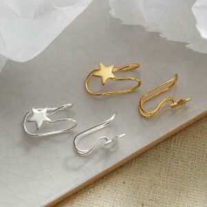 Sterling Silver and gold plated Star Ear Cuffs sat on a marble tile with their shadow being cast