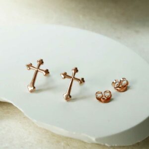 Rose Gold Plated Cross Stud Earrings on curved white background