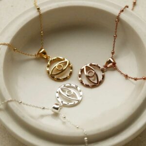 Evil eye necklaces on plate. Silver evil eye pendant, gold evil eye pendant and rose gold evil eye pendant.