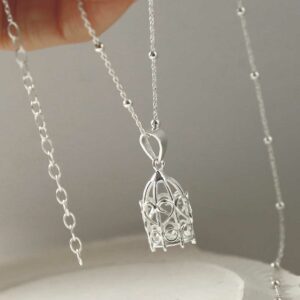 STERLING SILVER BIRDCAGE PENDANT NECKLACE WITH A WHITE BACKGROUND