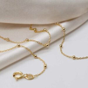 gold plated sterling silver satellite chain strewn on linen