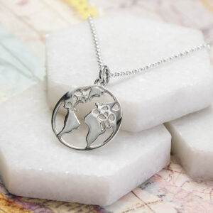 silver planet earth pendant necklace on marble slabs