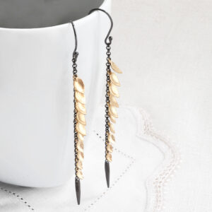 dark rhodium chain and gold plated leaves earrings hanging off white mug