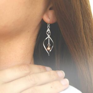 sterling silver twisted dangly earrings with centre rose gold ball on model