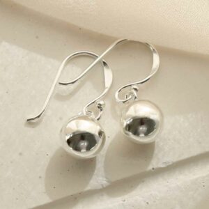 silver single ball dangly earrings laid on tile