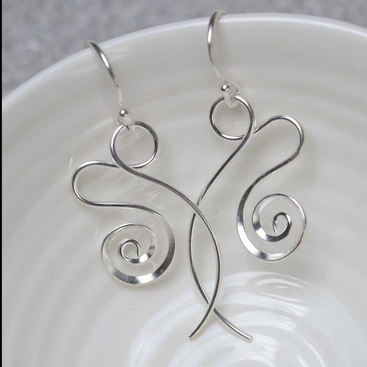 Sterling Silver Twirling Ribbon Dangly Earrings on jewellery dish