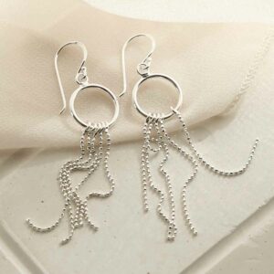 silver tassel on hoop dangly earrings strewn on linen