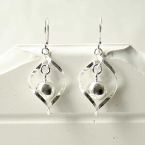 silver twisted earrings with central ball hanging on tile