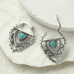 silver exotic hoops with turquoise triangle leaning on tile