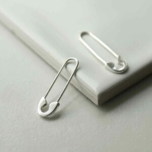 silver safety pin earrings leaning on tile