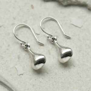 silver tiny pear shaped dangly earrings laid on stone