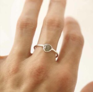 hand wearing silver ring with round labradorite stone