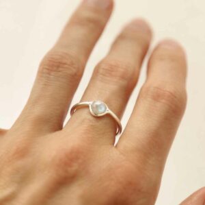 hand wearing silver ring with round moonstone stone