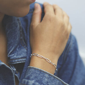 model wearing silver flattened link paperclip bracelet with denim jacket