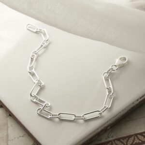 silver long chunky linked paperclip bracelet strewn on tile