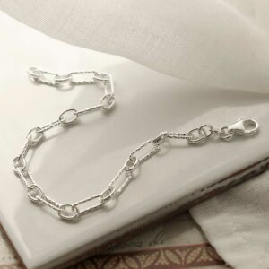 silver round and hammered linked bracelet strewn on tile