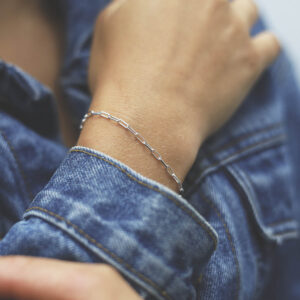 model wearing silver thinly linked paperclip bracelet with denim jacket