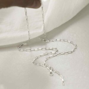 silver thinly linked paperclip necklace hanging from fingers