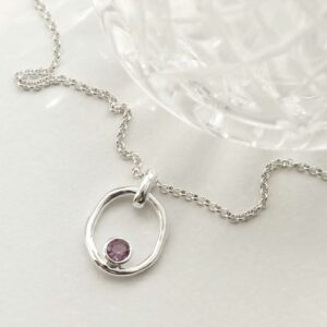 single amethyst gem in oval pendant on model