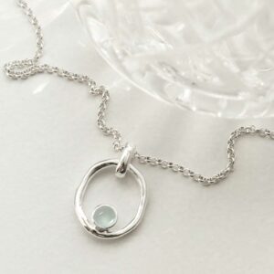 single blue topaz gem in oval pendant on model