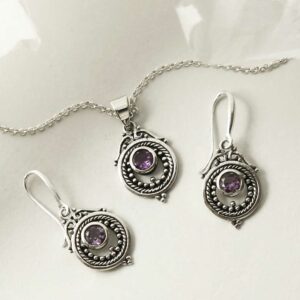 single amethyst gem in decorative earrings and necklace