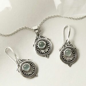 single blue topaz gem in decorative earrings and necklace