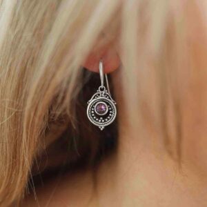 single amethyst gem in decorative dangly earrings on model