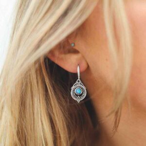 single opalite gem in decorative dangly earrings on model