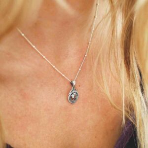 single blue topaz gem in decorative necklace on model