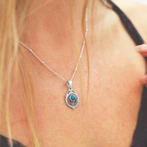 single turquoise gem in decorative necklace on model