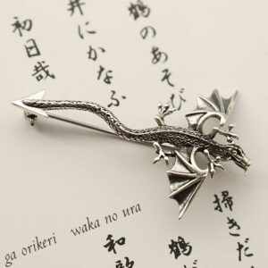 silver dragon brooch laid on parchment