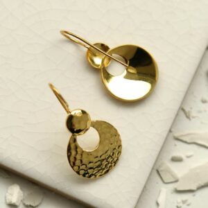 gold dangly round earrings sat on a tile