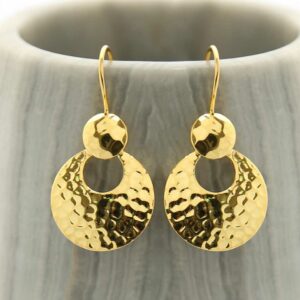 Gold dangly round earrings hanging out a grey pot