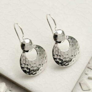 Silver dangly round earrings sat on a tile