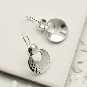 Silver dangly round earrings sat on a tile