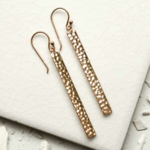 rose gold dangly straight earrings on a white tile