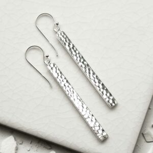 Silver dangly straight earrings on a white tile