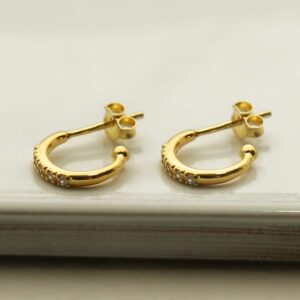 a pair of gold hoop stud earrings on a white tile