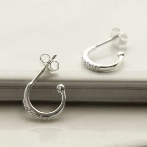 a pair of silver hoop stud earrings on a white tile