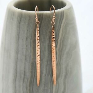 Rose Gold Icicle Dangly Earrings hanging on grey prop