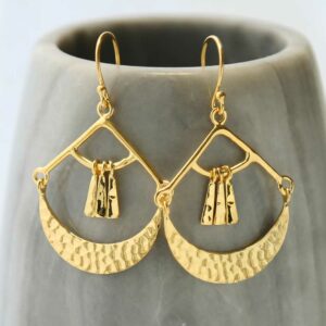 Gold Mayan Earrings hanging on grey cup background