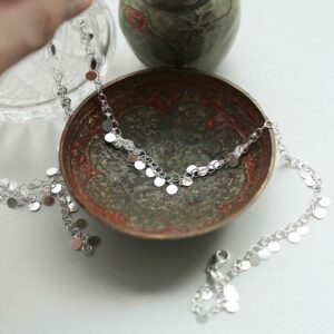 silver disc necklace strewn over bowl