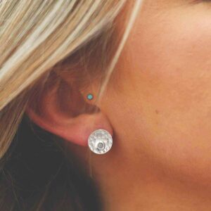 single blue topaz gem in centre of hammered stud earrings on model