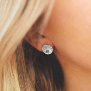 single turquoise gem in centre of hammered stud earrings on model