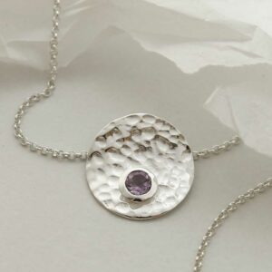 single amethyst gem in centre of hammered pendant