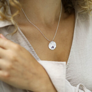 single amethyst gem in centre of hammered pendant on model