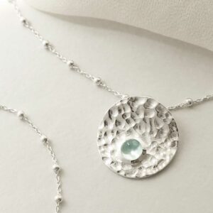 single blue topaz gem in centre of hammered pendant