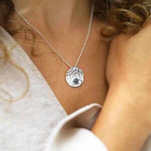 single labradorite gem in centre of hammered pendant on model