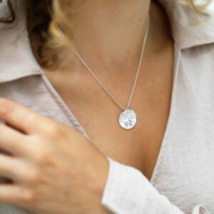 single moonstone gem in centre of hammered pendant on model